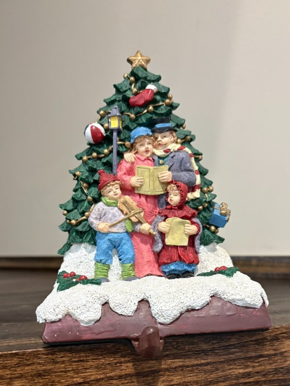 Vintage cast iron stocking holder caroling family at the tree, on a brown base